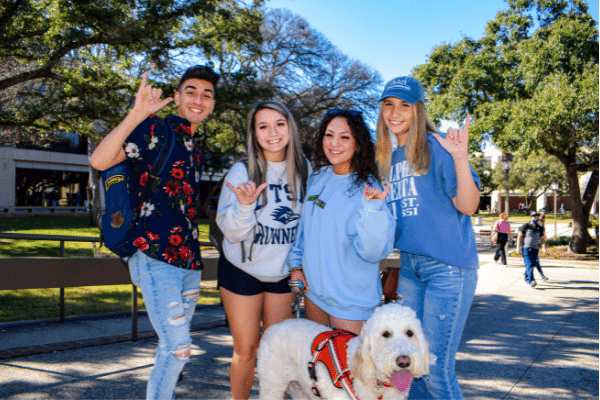 Four students and a dog on campus
